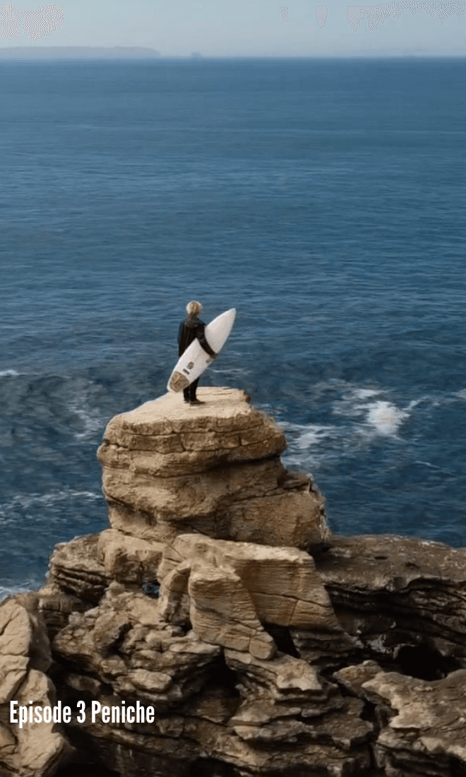 london standing on top of a rocky outcrop holding a surfboard